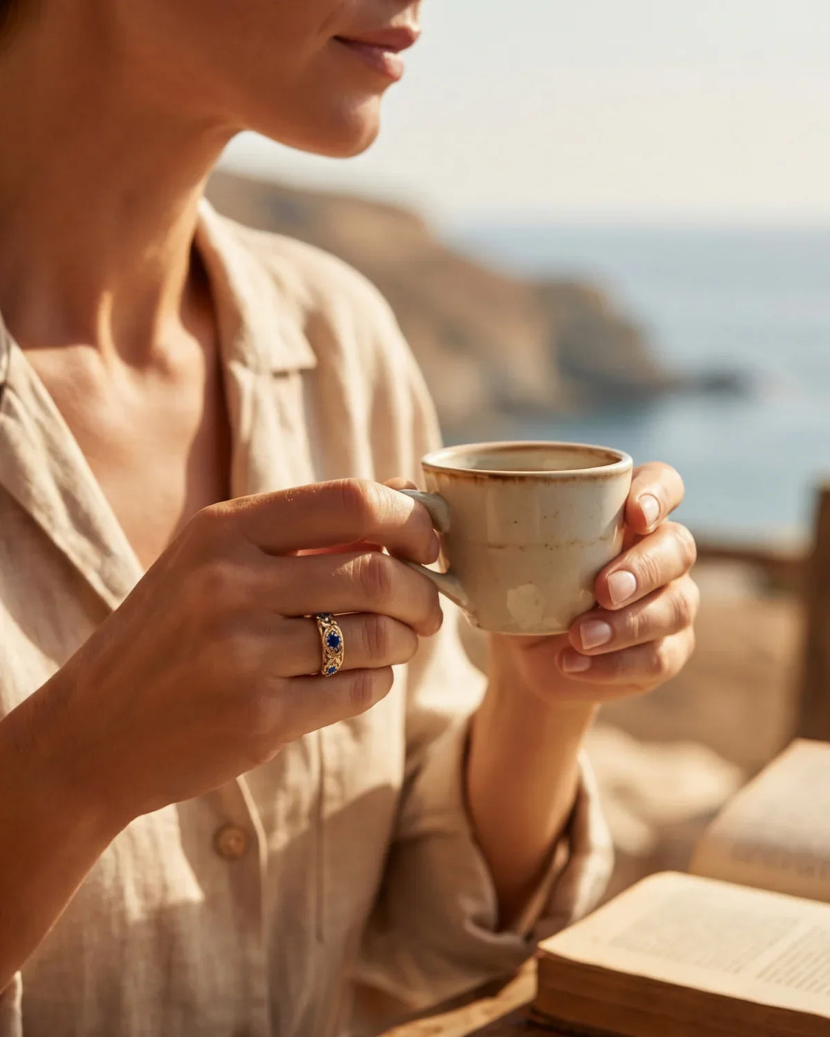 Gold ring with blue gemstones on hand holding ceramic cup