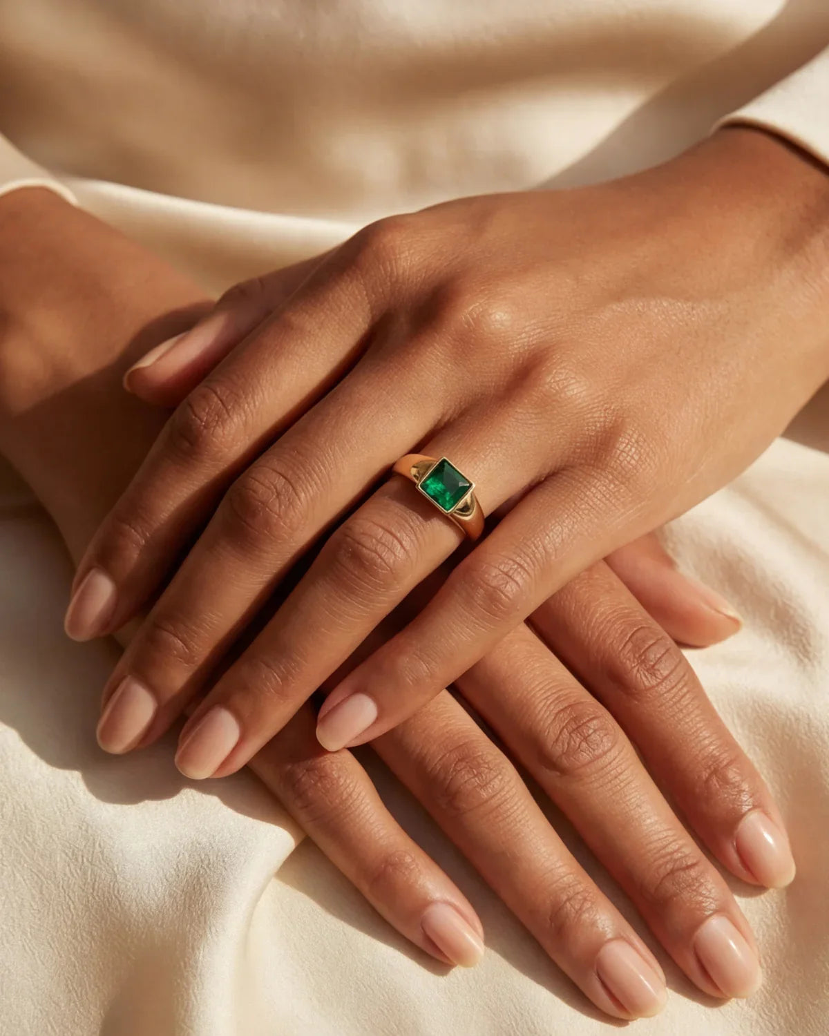 Close-up of a green square gemstone ring on a gold-tone band