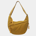 Yellow anti-theft crossbody bag with curved hobo shape, adjustable strap, and zipper detail.