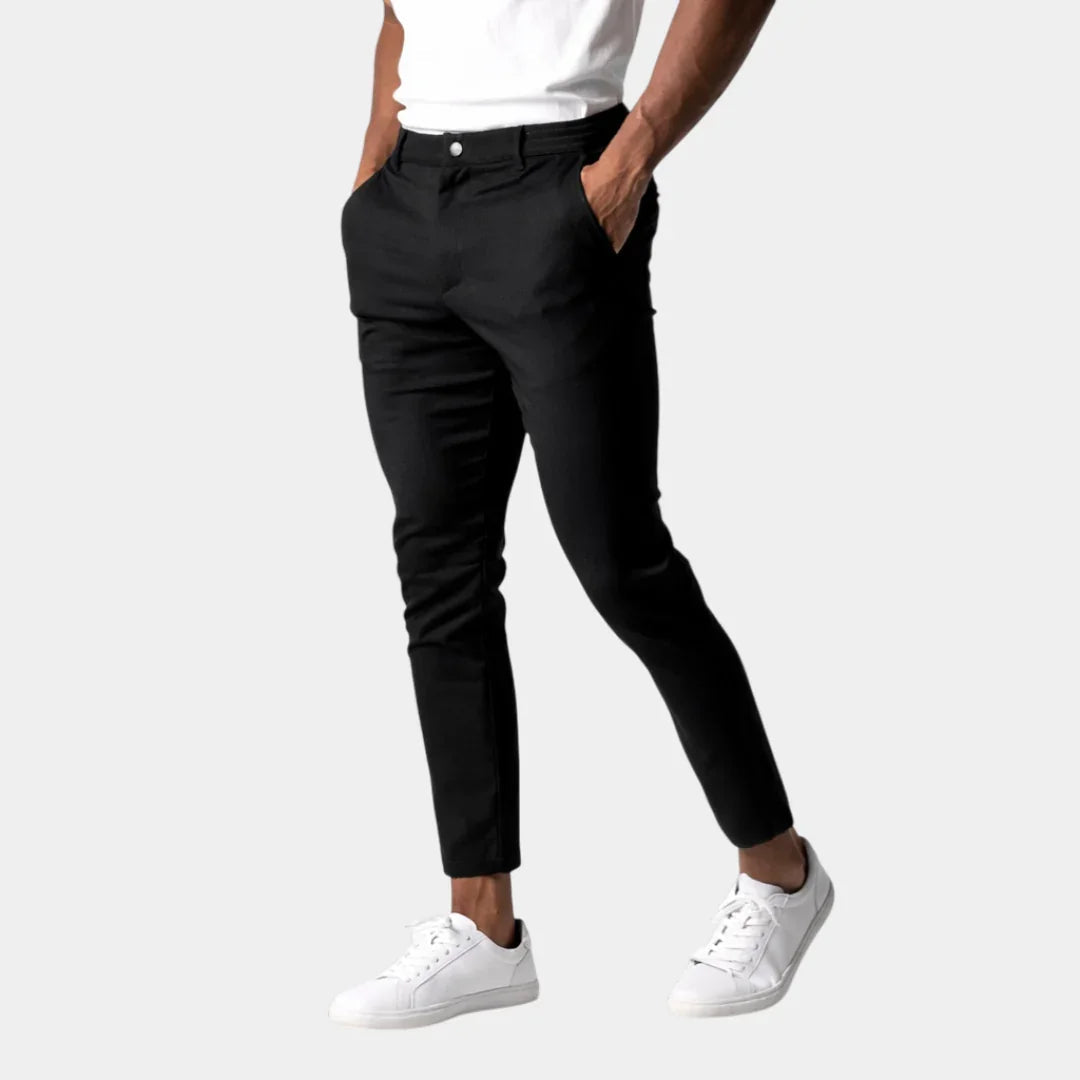 Black chino pants with button closure, front pockets, and tapered ankle length.