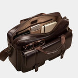 Brown leather briefcase open, showing document slots, zippers, and internal compartments
