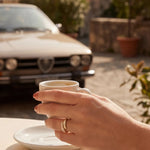 Gold adjustable ring on a hand holding a cup