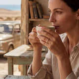 Gold ring with clear stones, visible while a woman holds a cup