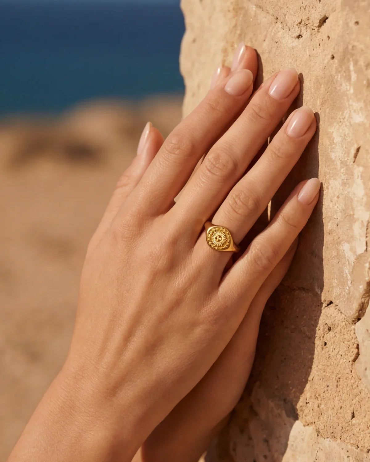 Gold-tone ring featuring a round, engraved sunburst motif on a slim band