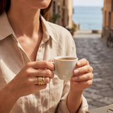 Gold-tone ring with textured curved band and small clear gemstone accents