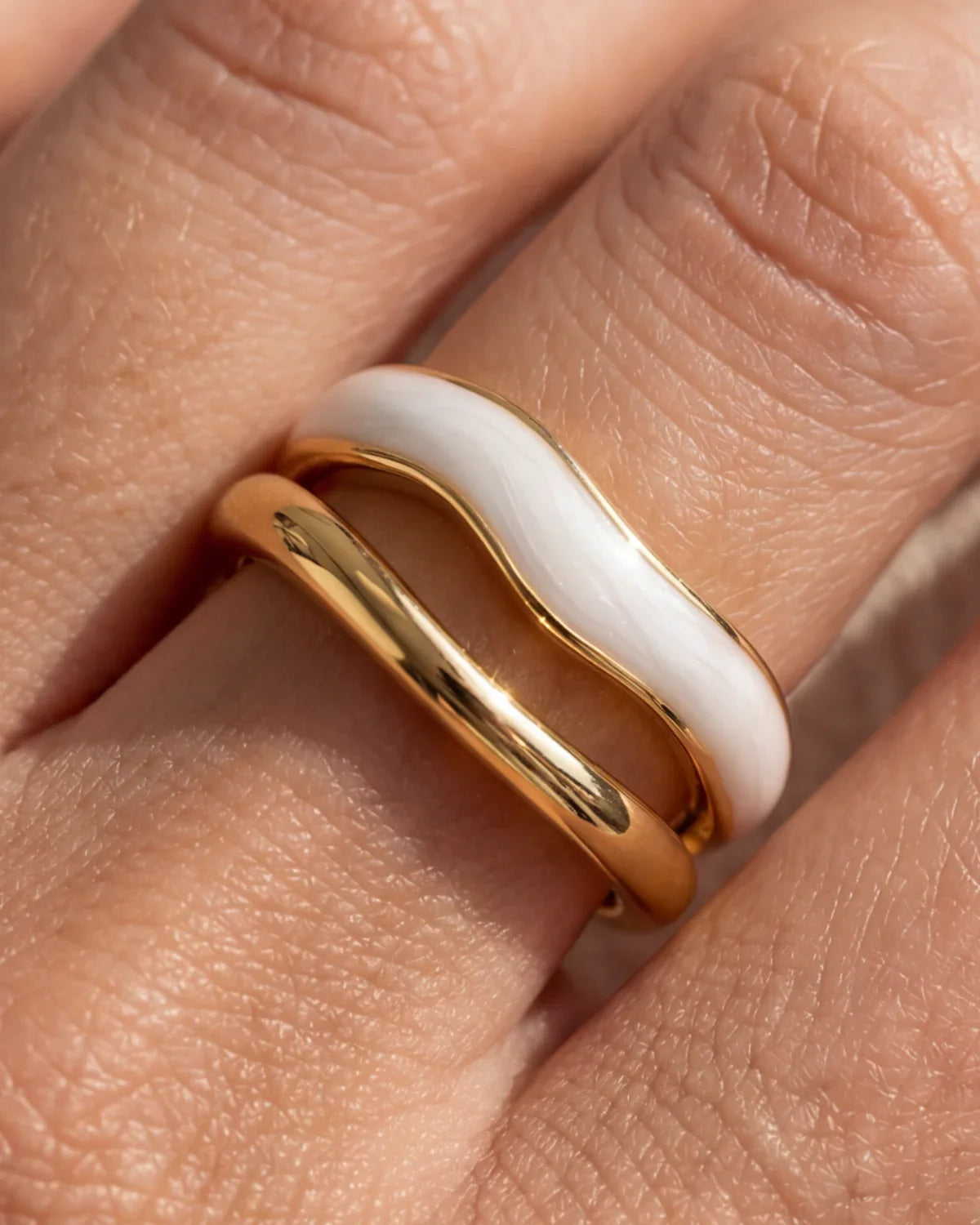 Close-up: adjustable gold ring with white inlay stripe and polished finish