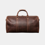 Dark brown leather travel bag with top handles, centered straps, and side zippers