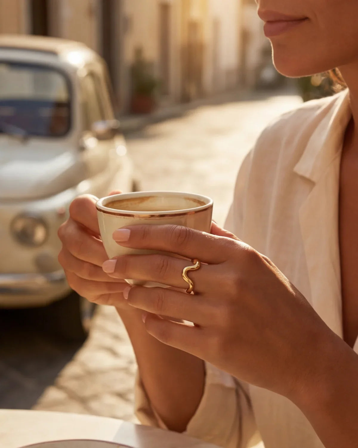 Gold wavy ring on finger holding a coffee cup