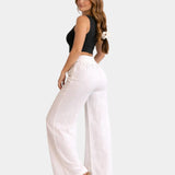 White high-waist wide-leg pants with gold chain belt detail, side view