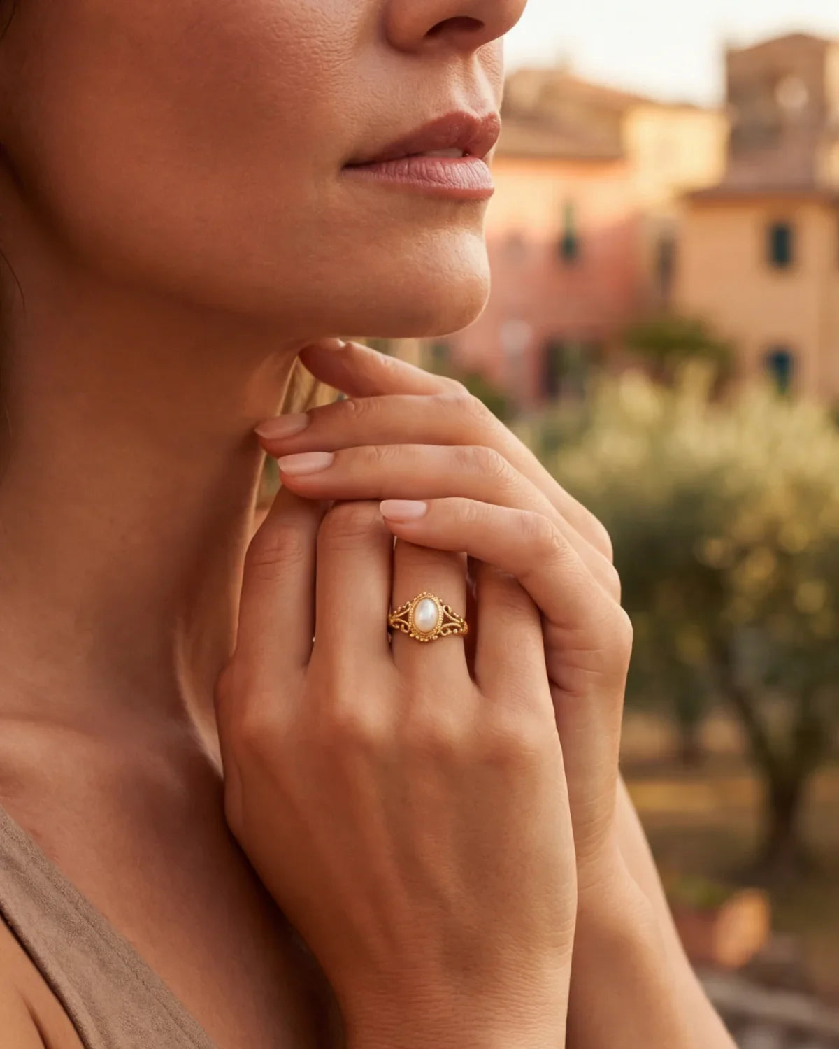 Gold oval-pearl ring with detailed bezel, worn on finger