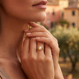 Gold oval-pearl ring with detailed bezel, worn on finger