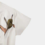 White short-sleeve wrap dress fabric close-up with botanical leaf print