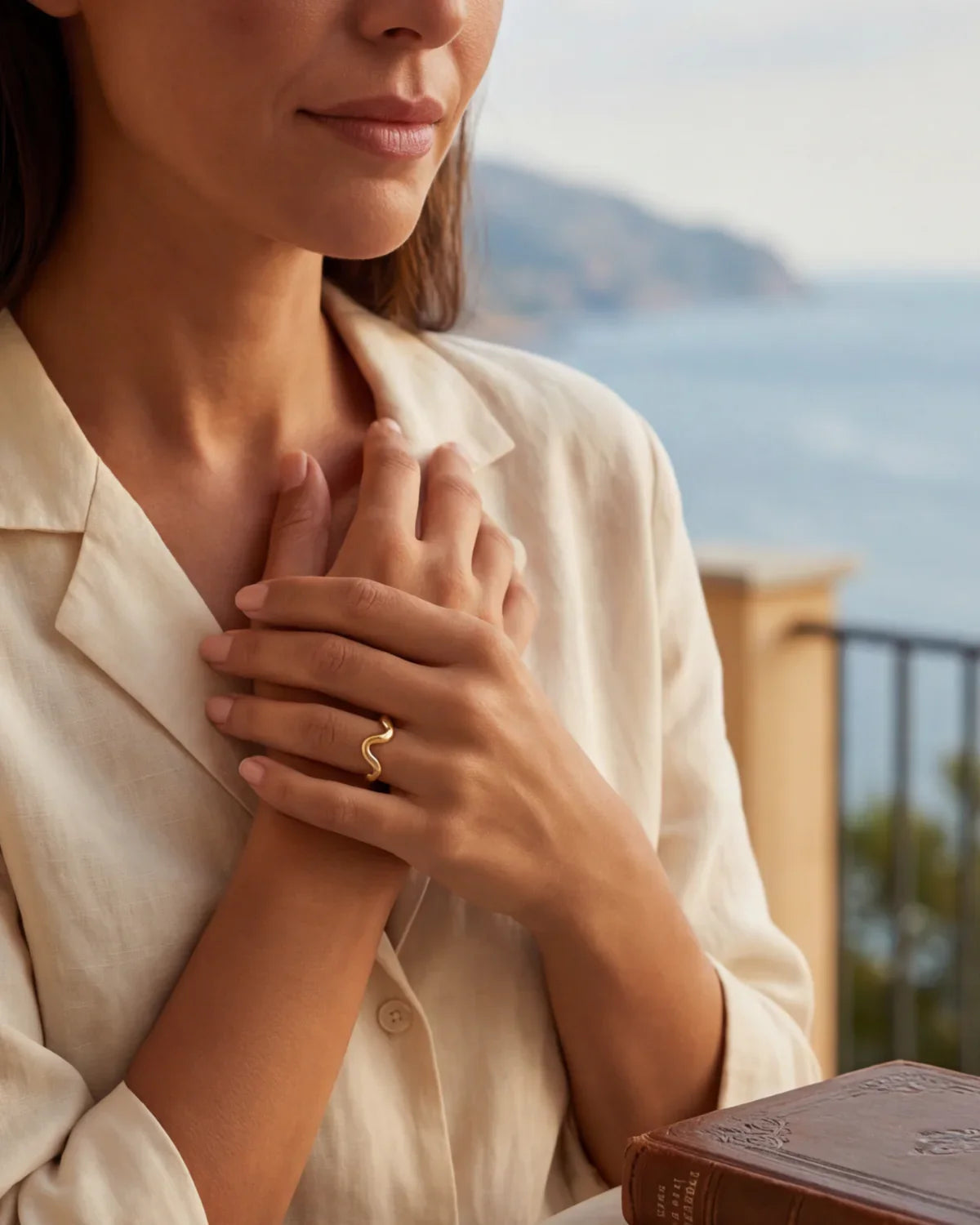 Gold wavy ring on finger with a white blouse sleeve