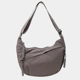 Gray anti-theft crossbody bag with curved hobo shape, adjustable strap, and zipper pull.