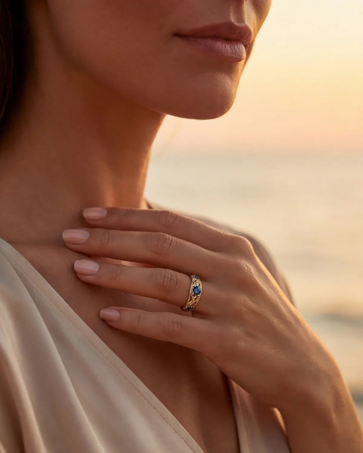 Gold ring with blue gemstones on finger, oval center setting