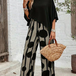 Black asymmetrical blouse with draped sleeves and wide-leg boho pants, bold black dot print
