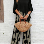 Black asymmetrical top with flutter sleeves and wide-leg boho pants, black-on-cream abstract dot print