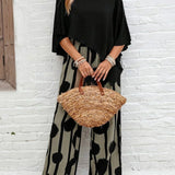 Black asymmetrical top with flutter sleeves and wide-leg boho pants, black-on-cream abstract dot print