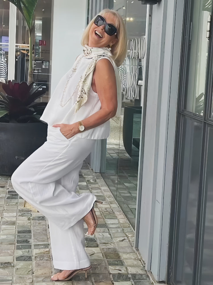 White sleeveless top and wide-leg pants with draped beaded scarf
