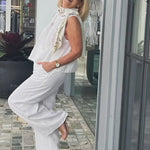 White sleeveless top and wide-leg pants with draped beaded scarf