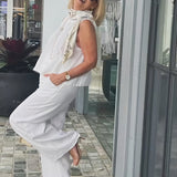 White sleeveless top and wide-leg pants with draped beaded scarf
