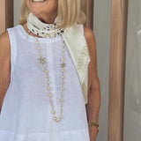White sleeveless top and wide-leg pants with long beaded necklace and scarf