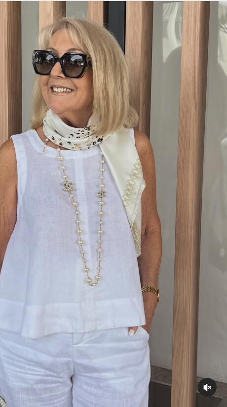 White sleeveless top and wide-leg pants with long beaded necklace and scarf