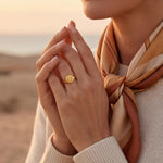 Gold-tone sunburst ring with a round engraved face on the top of the band