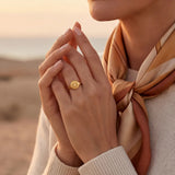 Gold-tone sunburst ring with a round engraved face on the top of the band