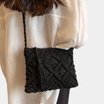 Black woven shoulder bag worn crossbody, textured front and braided strap