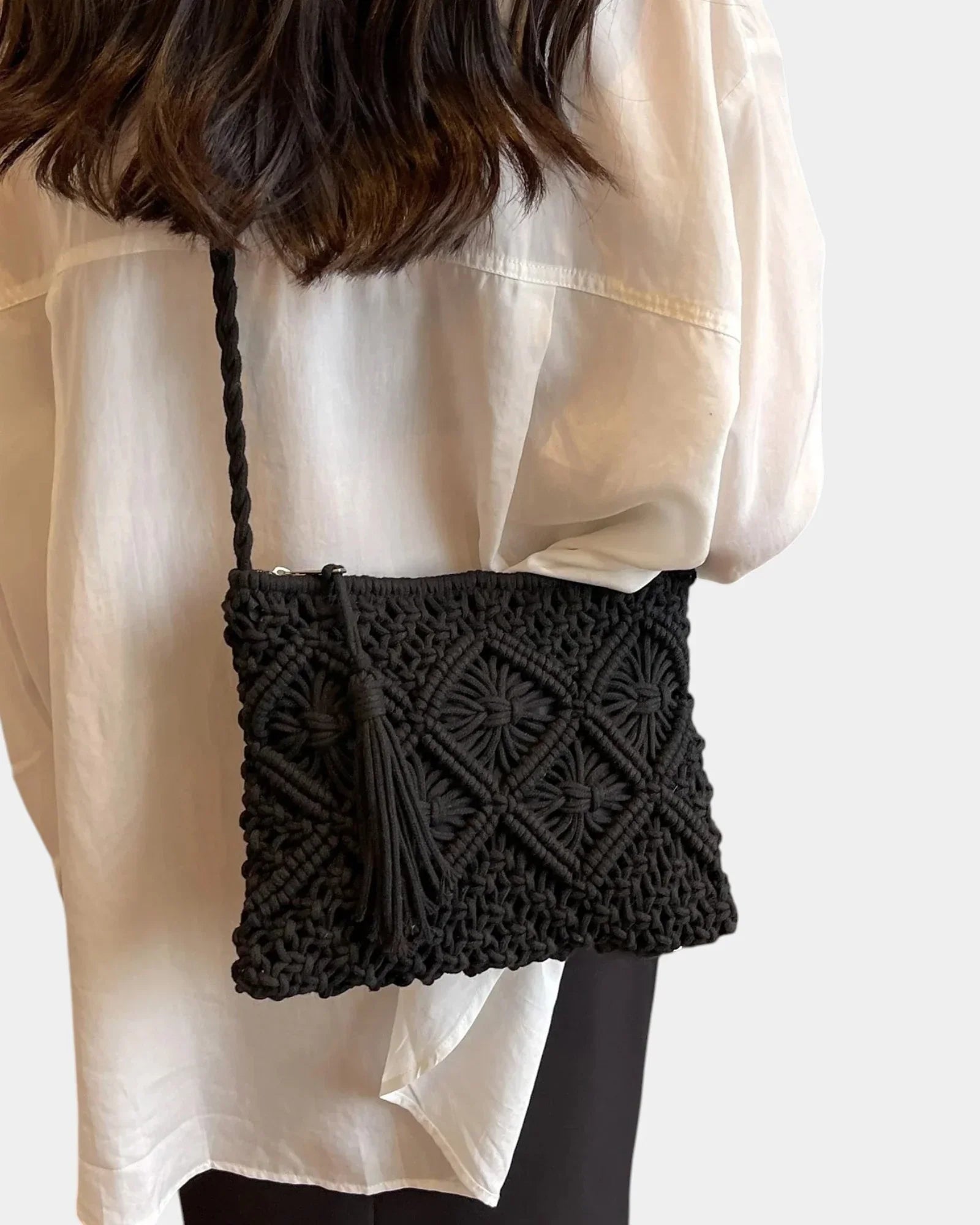 Black woven shoulder bag worn crossbody, textured front and braided strap