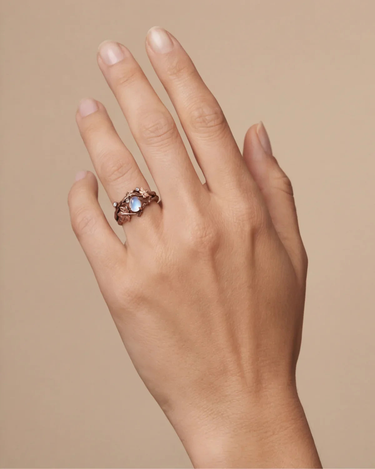 Bronze branch-effect ring with oval opalescent blue cabochon and halo of small stones