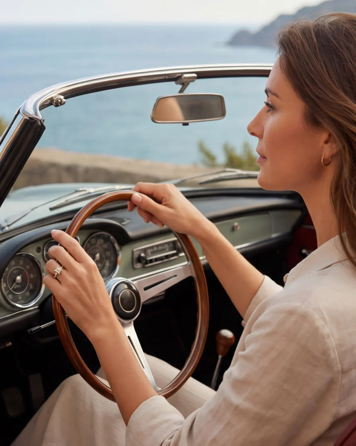Gold ring with clear cluster stone on finger gripping a car steering wheel