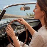 Gold ring with clear cluster stone on finger gripping a car steering wheel