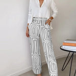 Two-piece outfit: white blouse with belt; wide-leg cream pants with gray abstract blocks