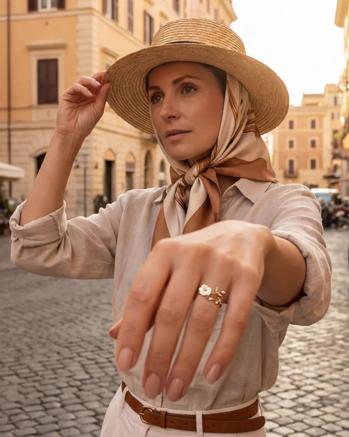Gold-tone ring with white flower detail and small clear stones on finger