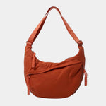 Orange anti-theft crossbody bag with curved hobo shape, adjustable strap, and side zipper.