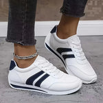 White lace-up orthopedic sneakers with navy stripe panels and textured outsole edge