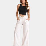 White high-waist wide-leg pants with gold chain belt detail