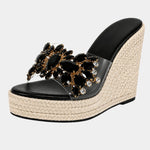 Black heeled platform sandals with dark jeweled floral strap and woven wedge