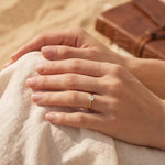 Small solitaire ring with round gemstone on finger