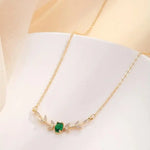 Gold pendant necklace with green leaf centerpiece and diamond-like accents