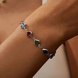 Silver-tone heart charm bracelet with dark blue, green, and red gemstone hearts