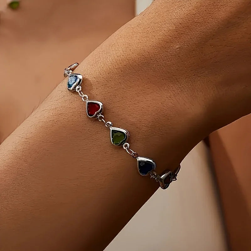 Silver-tone heart charm bracelet with dark blue, green, and red gemstone hearts