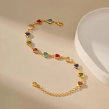 Gold-tone heart charm bracelet with multicolor enamel heart stones, flat lay