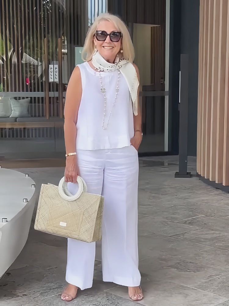 White sleeveless top and wide-leg pants with neck scarf and long necklace