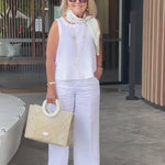 White sleeveless top and wide-leg pants with neck scarf and long necklace