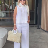 White sleeveless top and wide-leg pants with neck scarf and long necklace