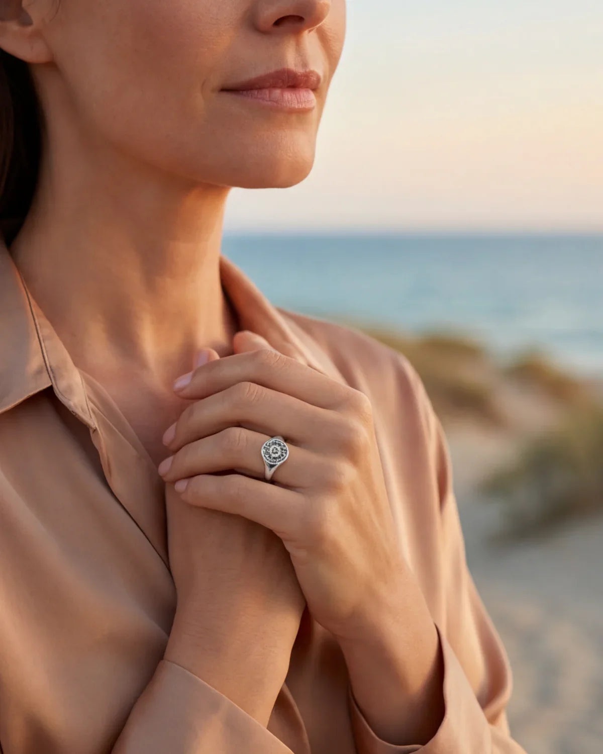 Silver-tone ring with a round engraved sunburst face on a smooth band