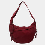 Burgundy anti-theft crossbody bag with curved hobo shape, adjustable strap, and zipper pull.